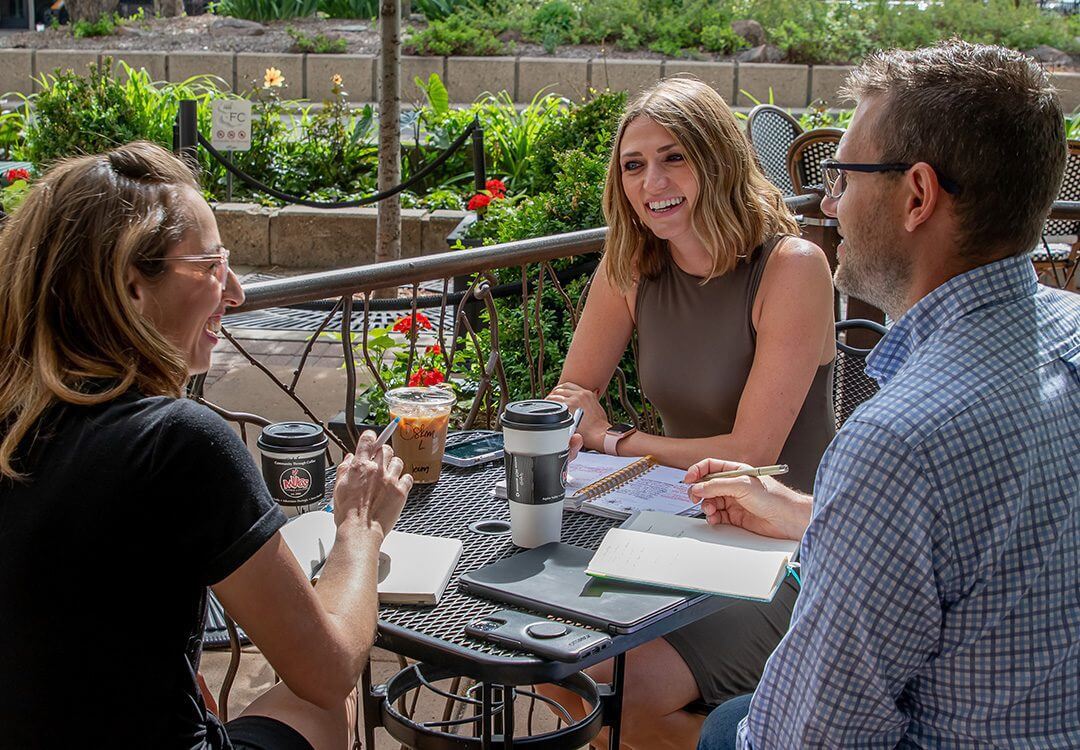 Three people drinking coffee outside