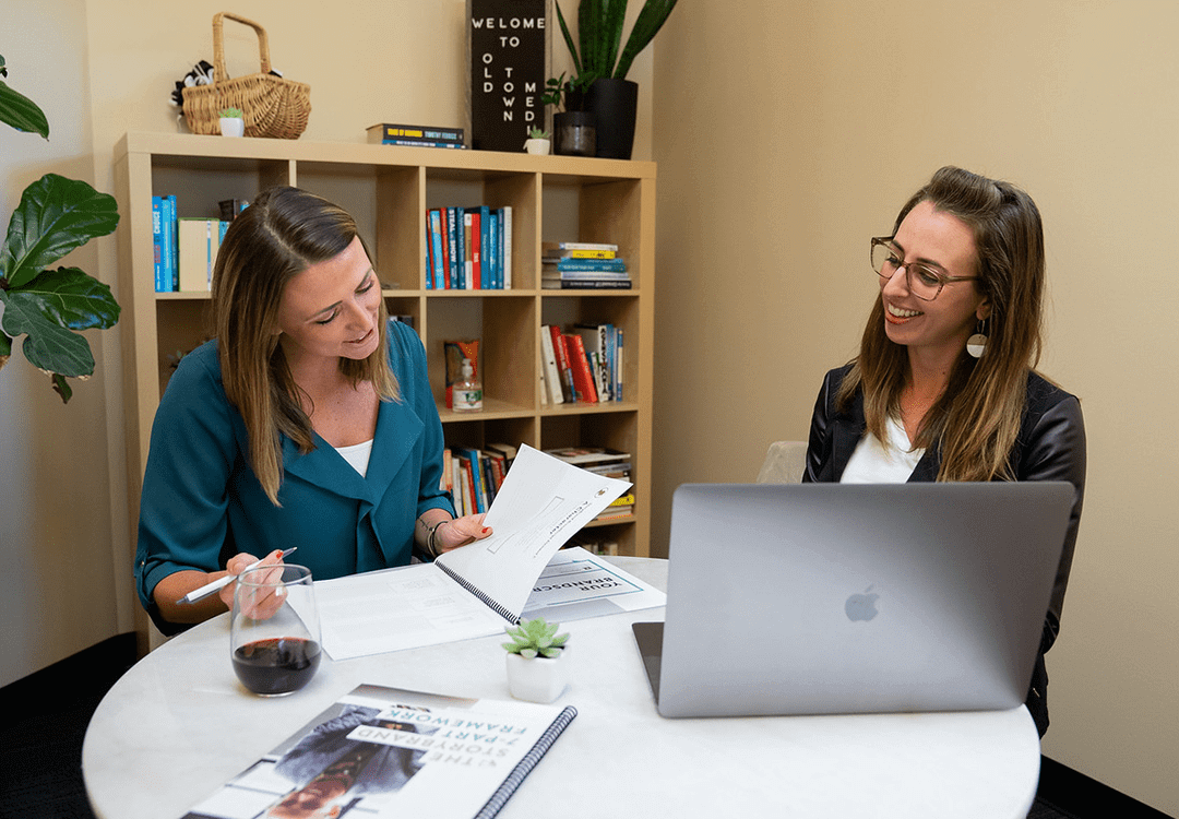 team members looking at paperwork two women sitting at a table discussing