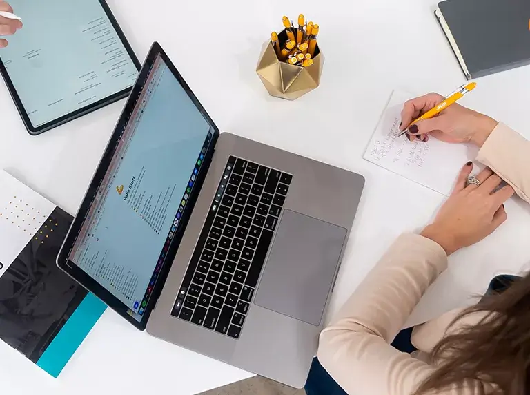 overhead-view-of-person-writing-something-with-laptop person working on writing something with laptop open next to them